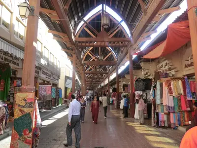 Überdachte Souk-Passage in Alt-Dubai mit Textilgeschäften und Fußgängern