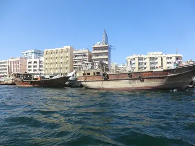 Traditionelle hölzerne Dhaus am Dubai Creek vor städtischer Bebauung