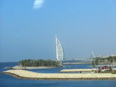 Küstenlandschaft von Dubai mit Wasser, Palmen und dem Burj Al Arab im Hintergrund